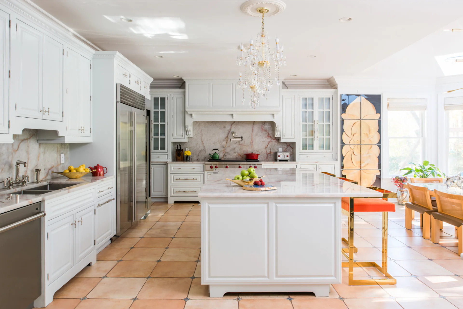 Bright, open-concept kitchen with white cabinetry, terracotta tile flooring, stainless steel appliances, and a large central island, designed by Lakbir Mahajan.