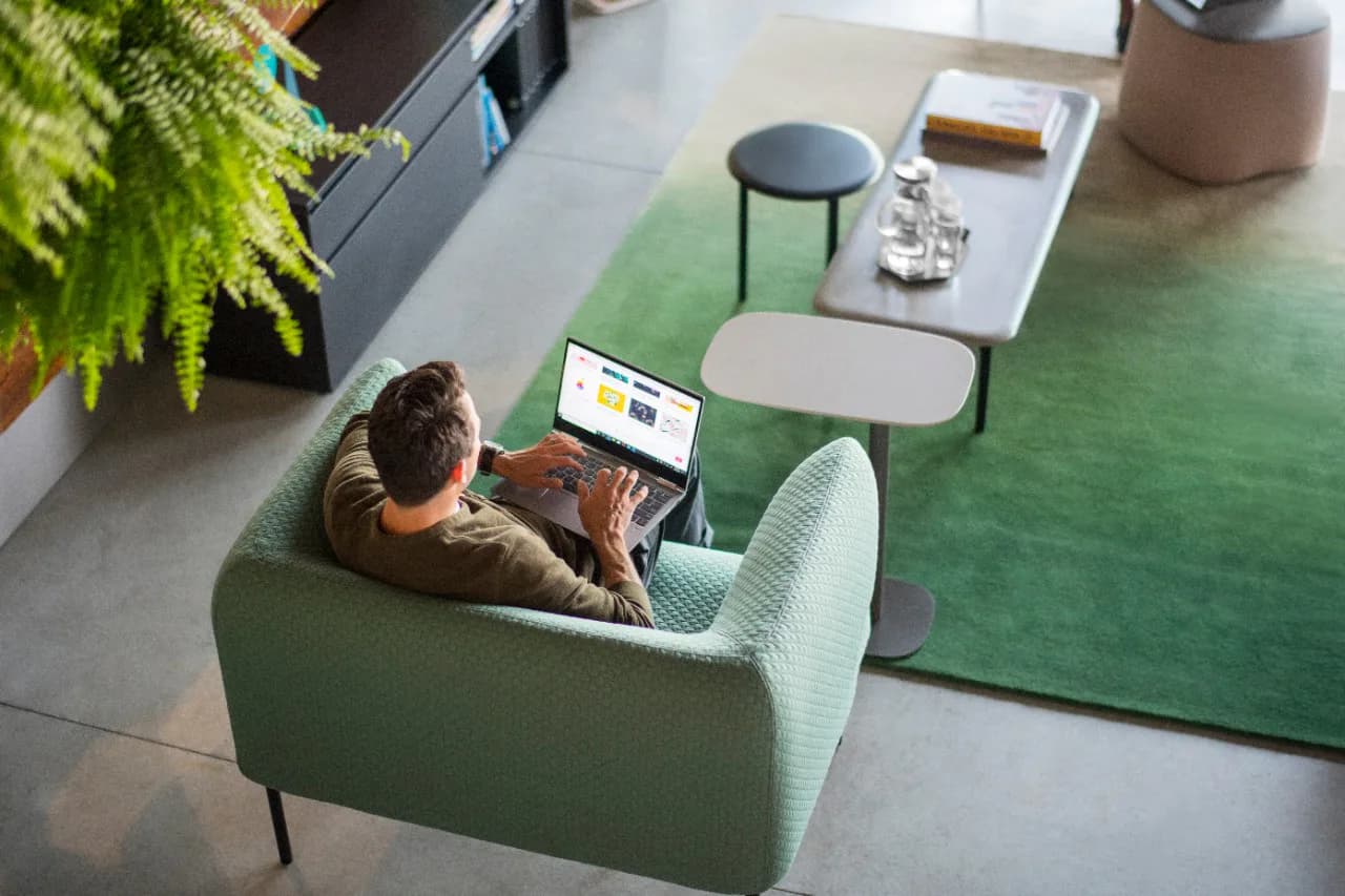 Modern office lounge with green upholstered seating, concrete flooring, and minimalist furnishings designed by Liam Han.