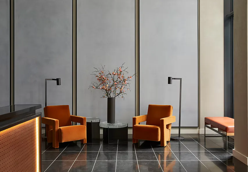 Modern interior lounge with burnt orange chairs, dark flooring, and floor-to-ceiling glass panels with decorative dried branches by Liong The.