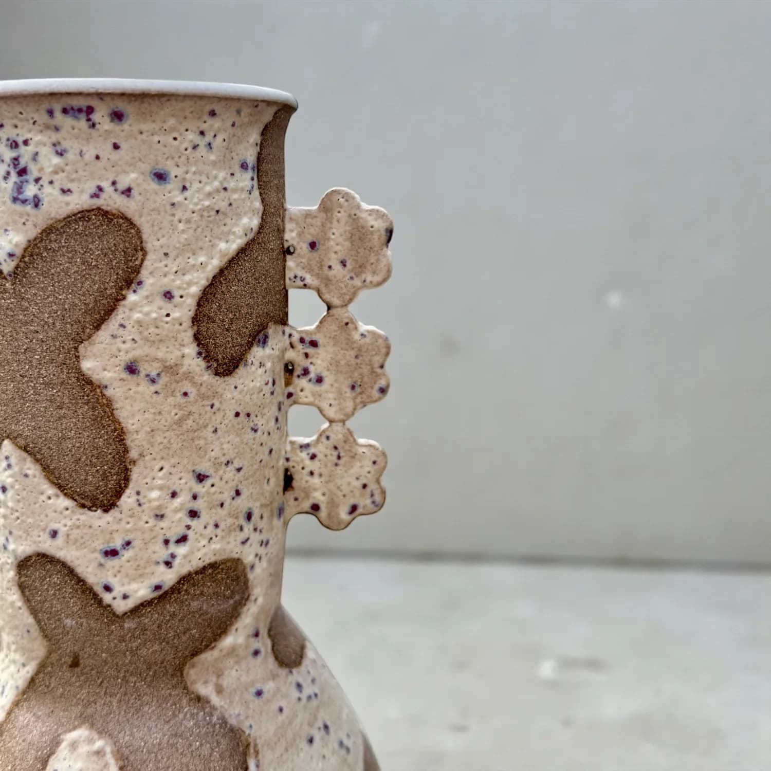 Textured ceramic vessel with organic spotted pattern in cream and brown tones, featuring decorative applied elements by Lisa Jakobsberg.