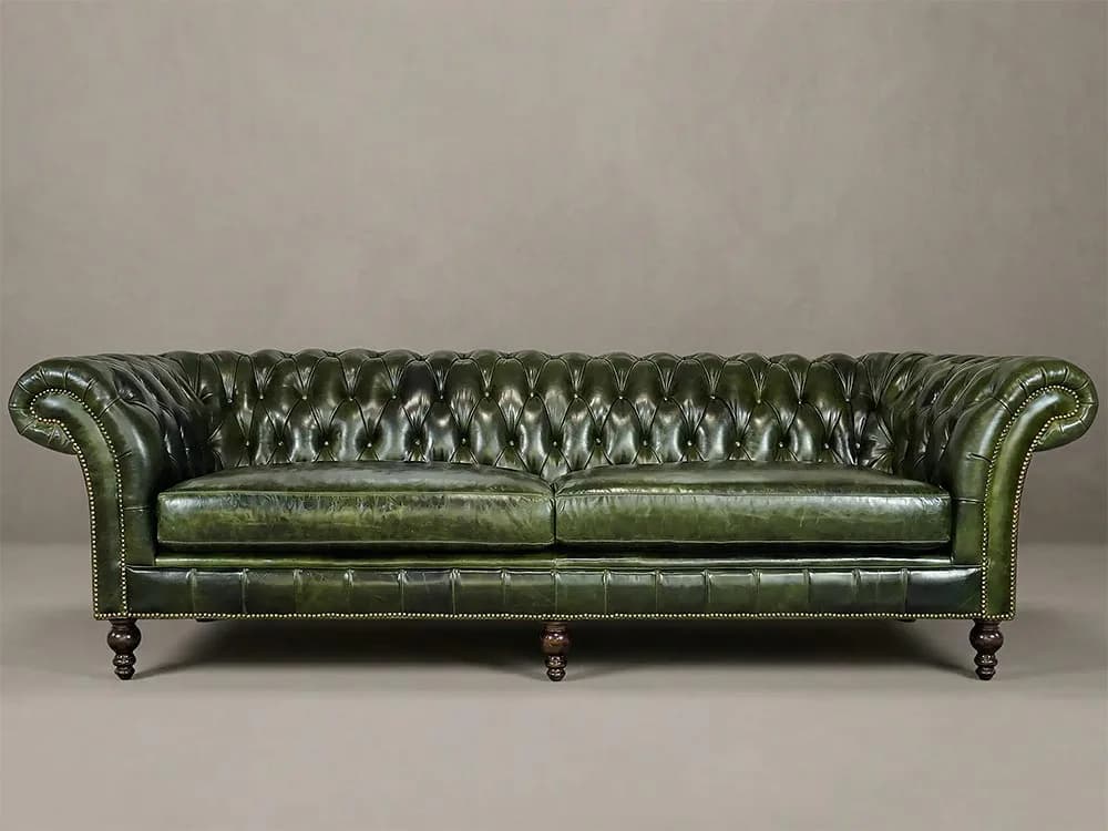 Green leather Chesterfield sofa with rolled arms and nailhead detailing on casters, showcasing upholstered furniture design by Liz Bartak.