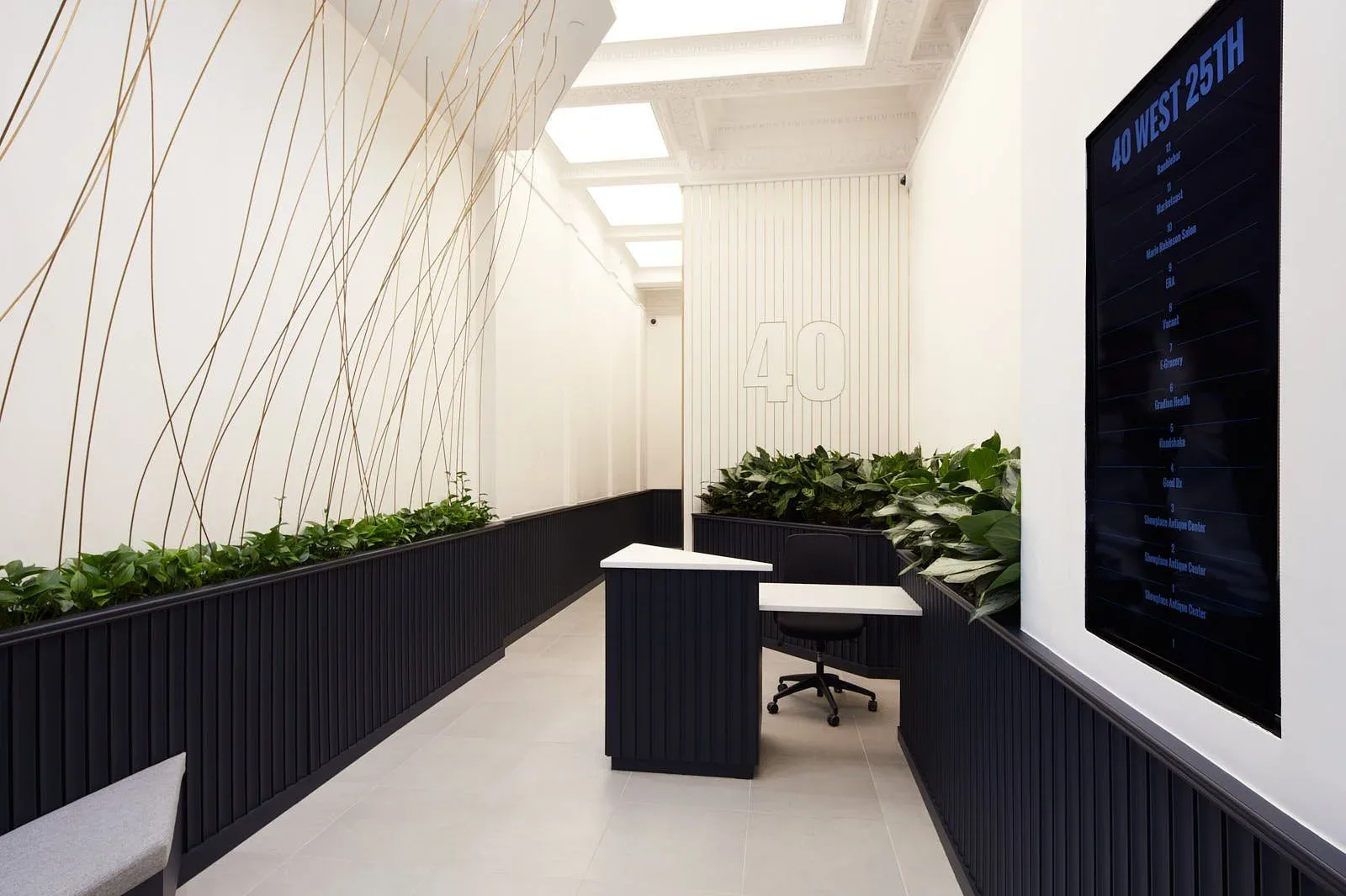 Modern office corridor with black ribbed wall paneling, white ceiling with skylights, living plant walls, and suspended linear elements by Lizi Gegenava.