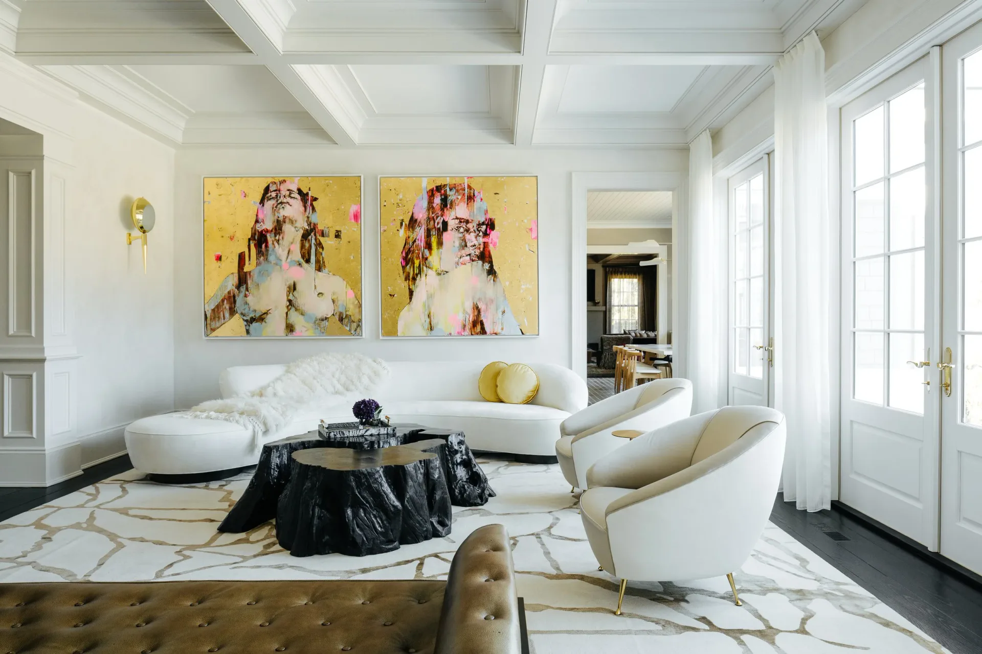 Bright modern living room with coffered ceiling, yellow abstract artwork, curved white furniture, marble flooring, and black accents by Lori Margolis.