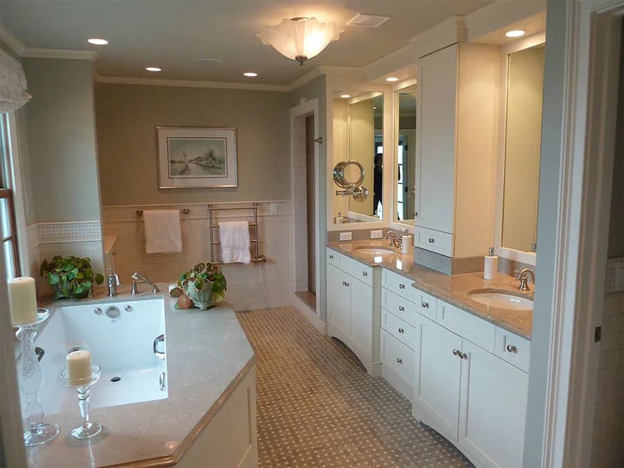 Luxurious master bathroom featuring dual vanities with white cabinetry, marble countertops, large mirror, soaking tub, neutral palette, and recessed lighting by Lorraine Frye.