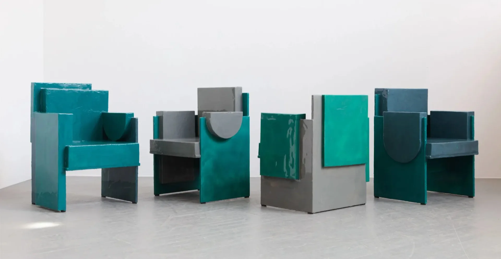 Collection of teal and gray modular furniture pieces arranged in a line, featuring geometric forms with mixed finishes by Luam Melake.