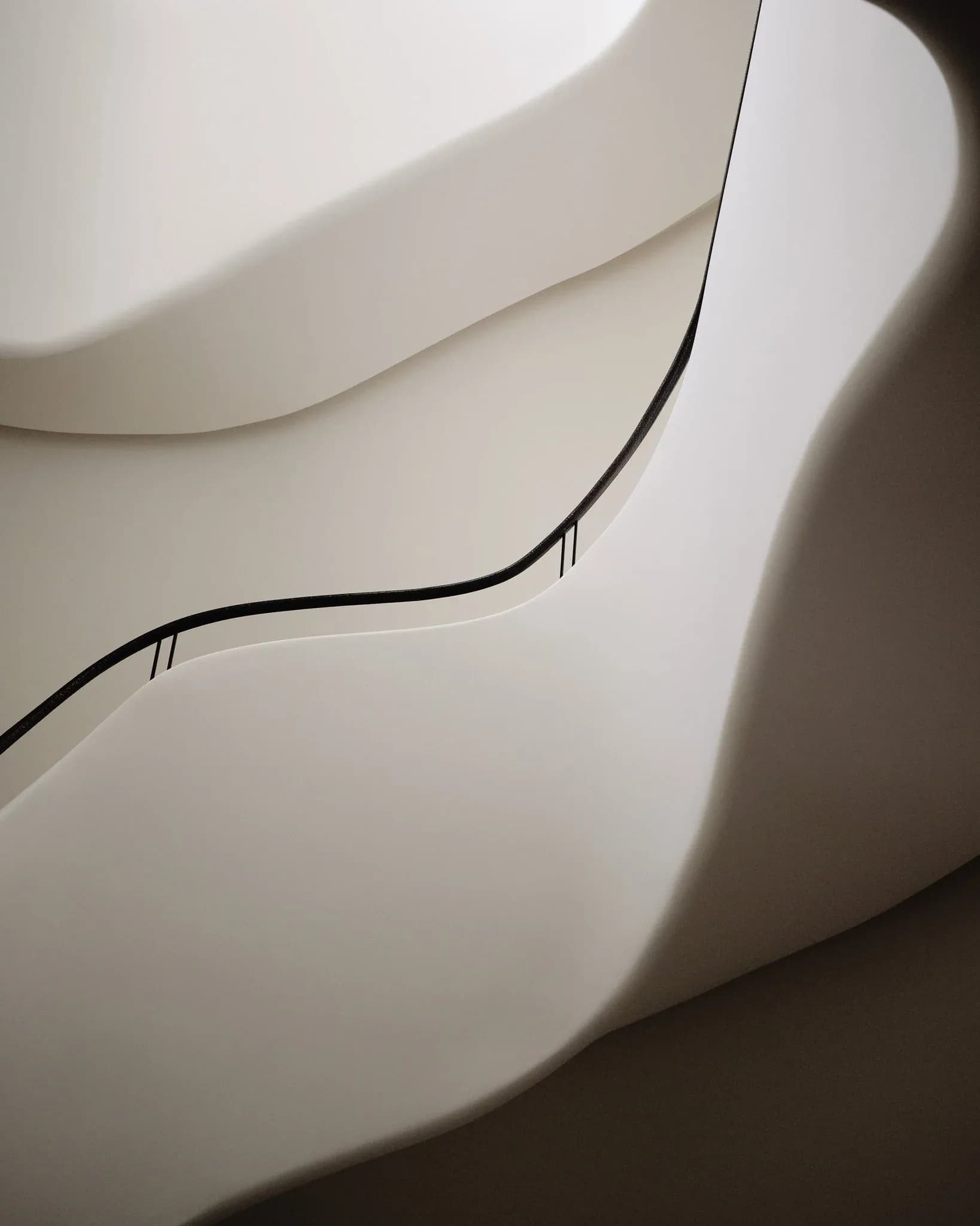 Curved white interior surfaces with integrated black cable management details, showcasing minimalist architectural design by Khanh Luu.