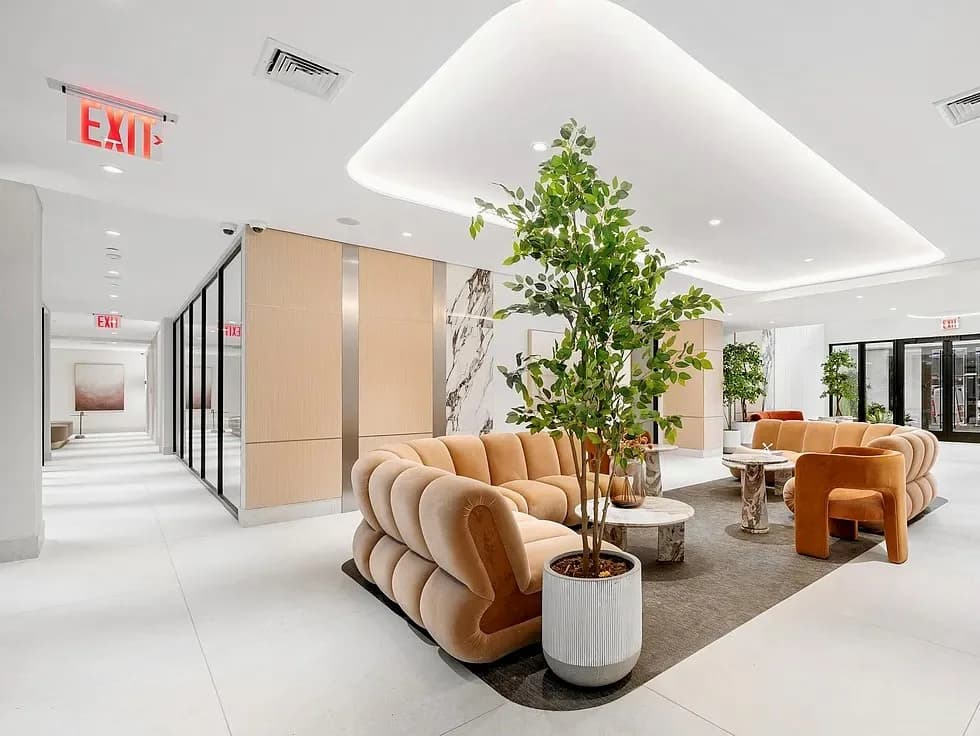 Modern commercial lobby with curved peach furniture, living plant installations, and geometric ceiling details by MacKenzie Reid.