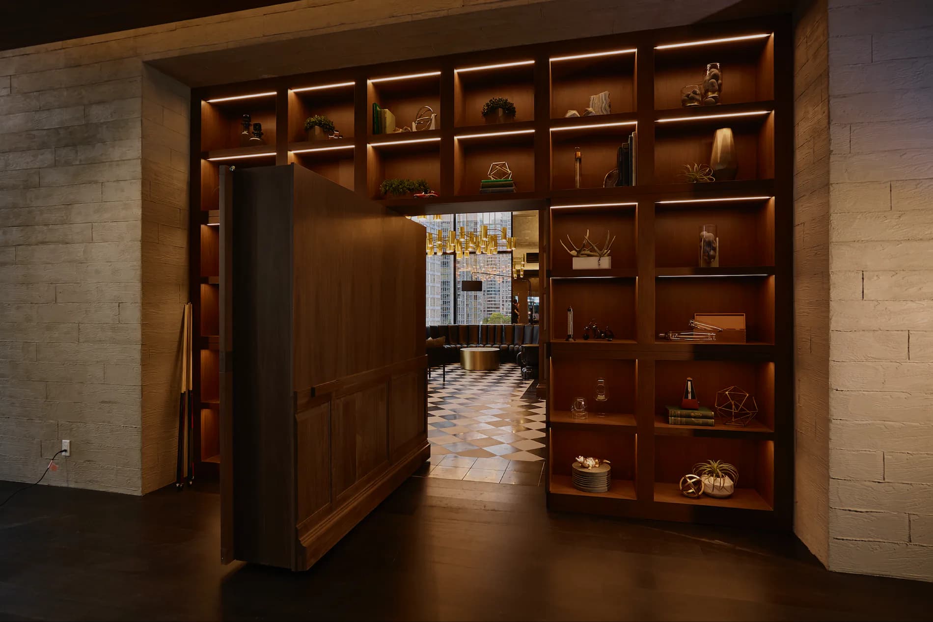 Hidden library with wood-lined shelving and warm lighting opens to reveal a patterned floor interior by Mahek Joshi.