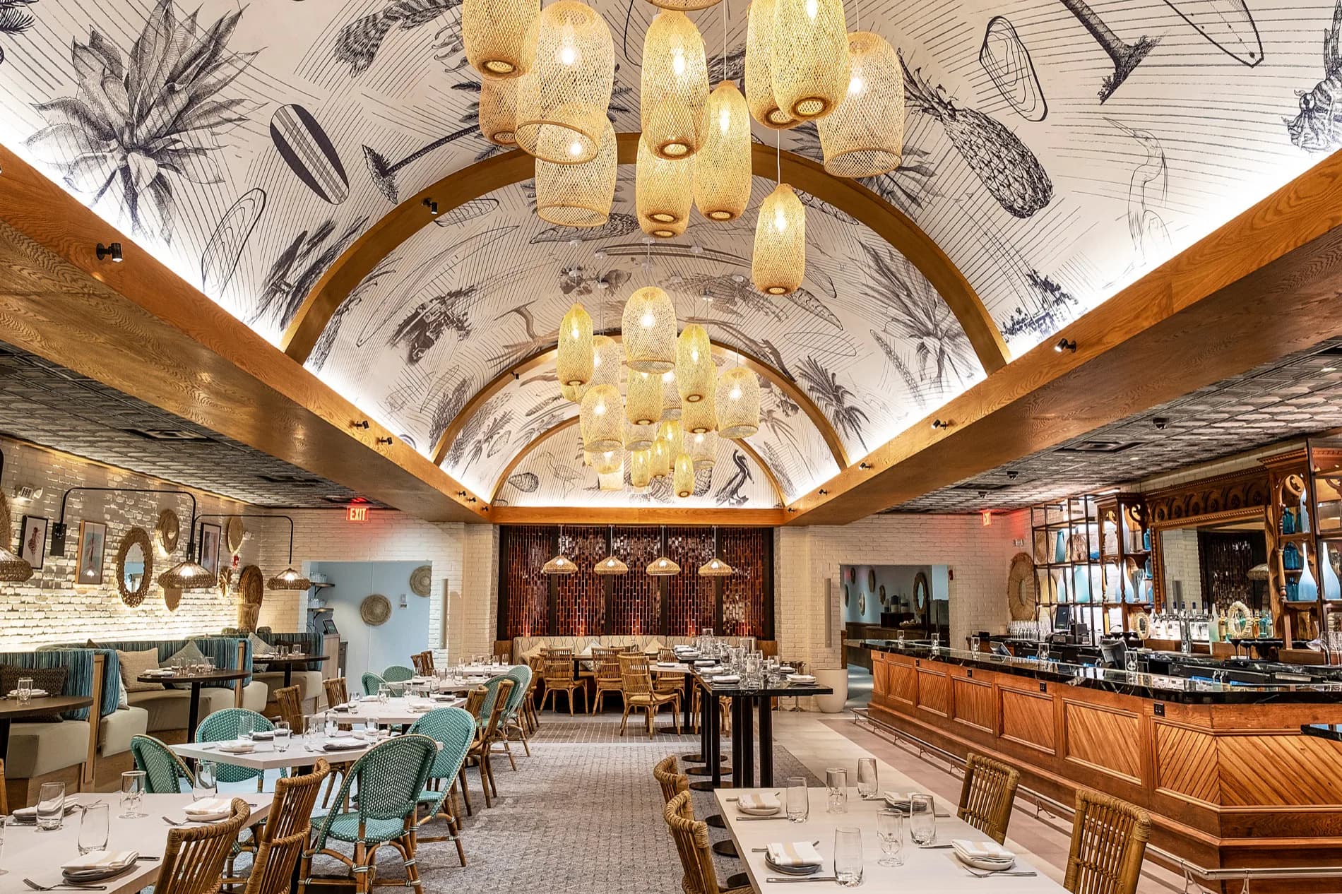 Elegant barrel-vaulted restaurant interior with cream wallpapered ceiling, wood beams, glass pendant lights, turquoise dining chairs, and wooden bar by Mahek Joshi.