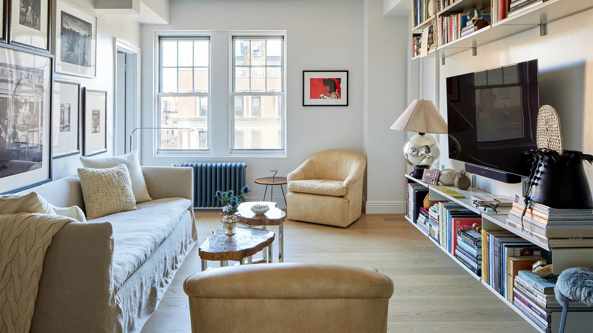 Bright living room with light blue sofa, cream armchair, wooden coffee table, and built-in media shelving, designed by Margaret Costello.