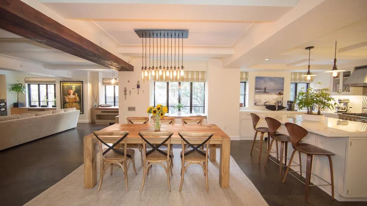 Open-plan dining and kitchen interior with natural wood table, pendant lighting, and coastal-inspired palette by Marie Burgos.