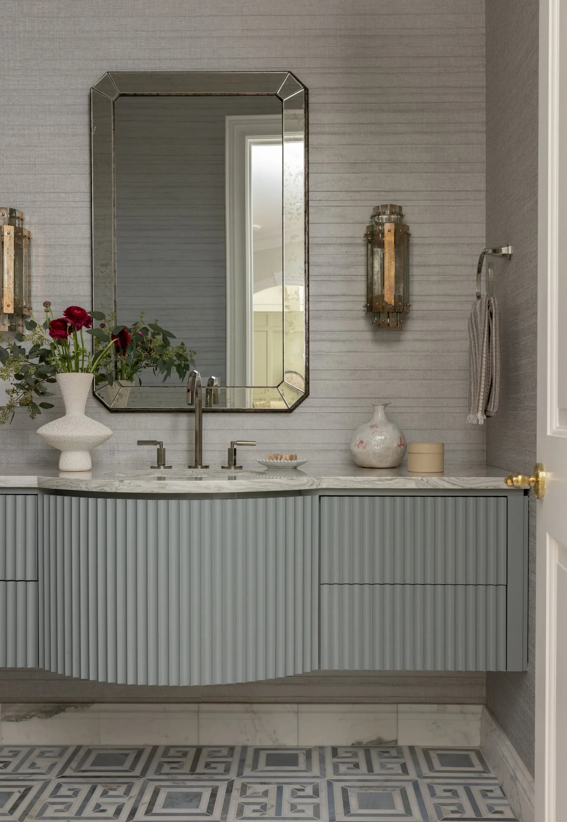 Modern bathroom vanity with ribbed gray cabinetry, white marble countertop, and framed mirror by Marina Mitchell.