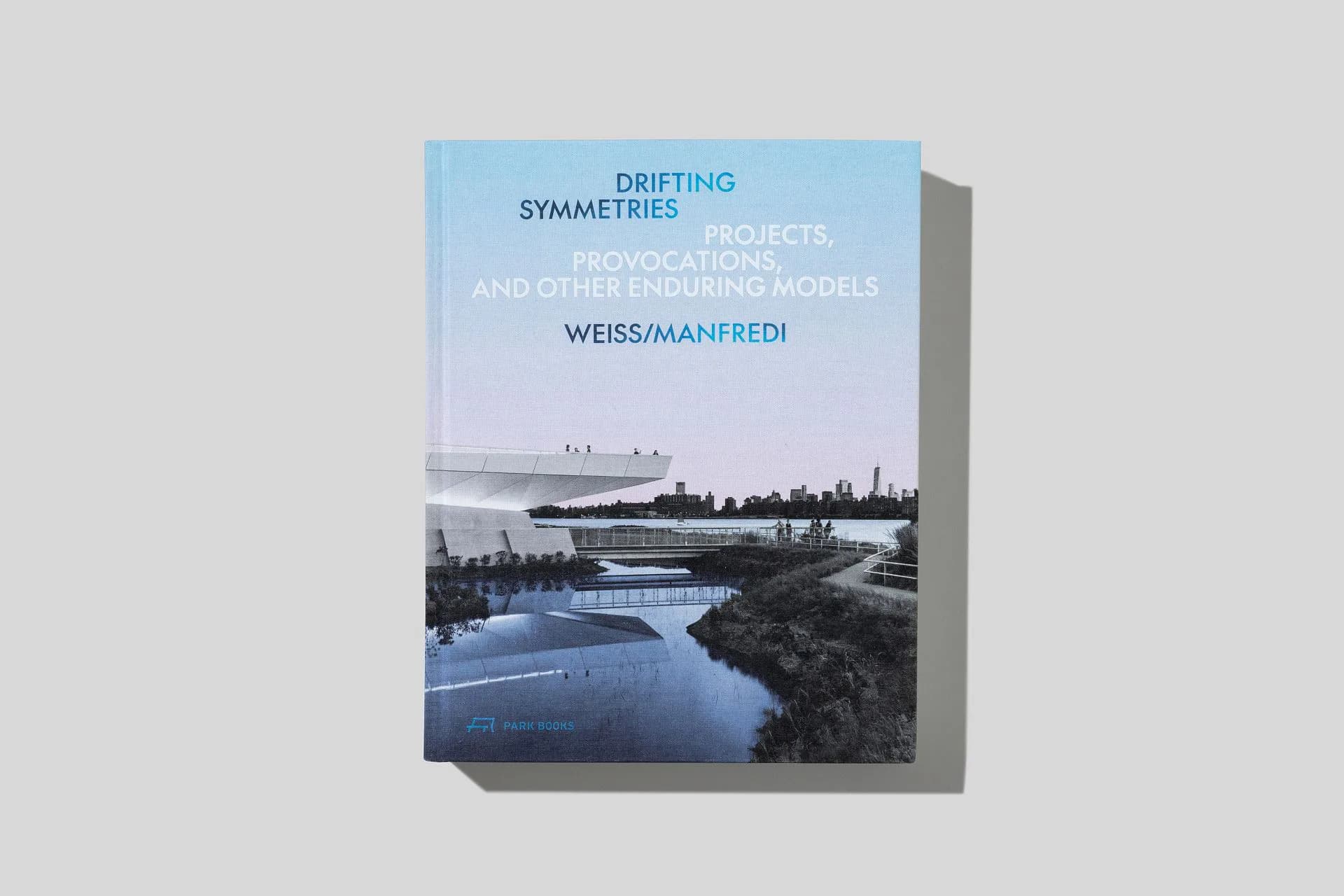 Book cover for 'Drifting Symmetries' featuring a landscape photograph of a winding river through forested terrain with blue water reflections, designed by Weiss/Manfredi.