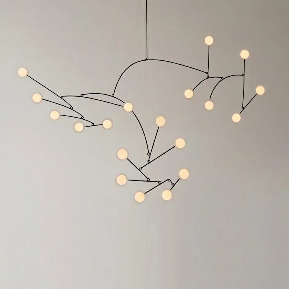 Sculptural mobile pendant lighting installation with branching metal arms and cream-colored spherical elements suspended against neutral backdrop by Mary Wallis.