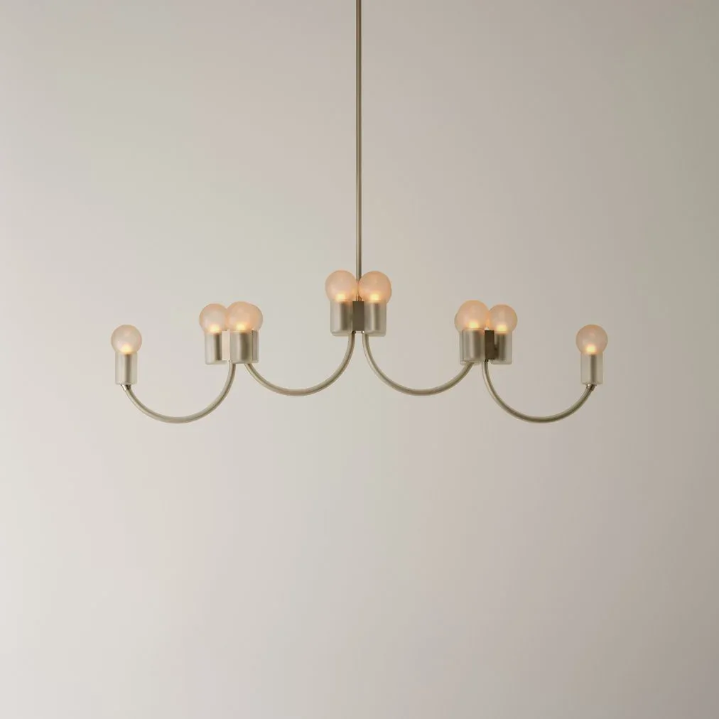 A contemporary brass and wood chandelier with five curved arms and cylindrical wood accents suspended from the ceiling by Mary Wallis.