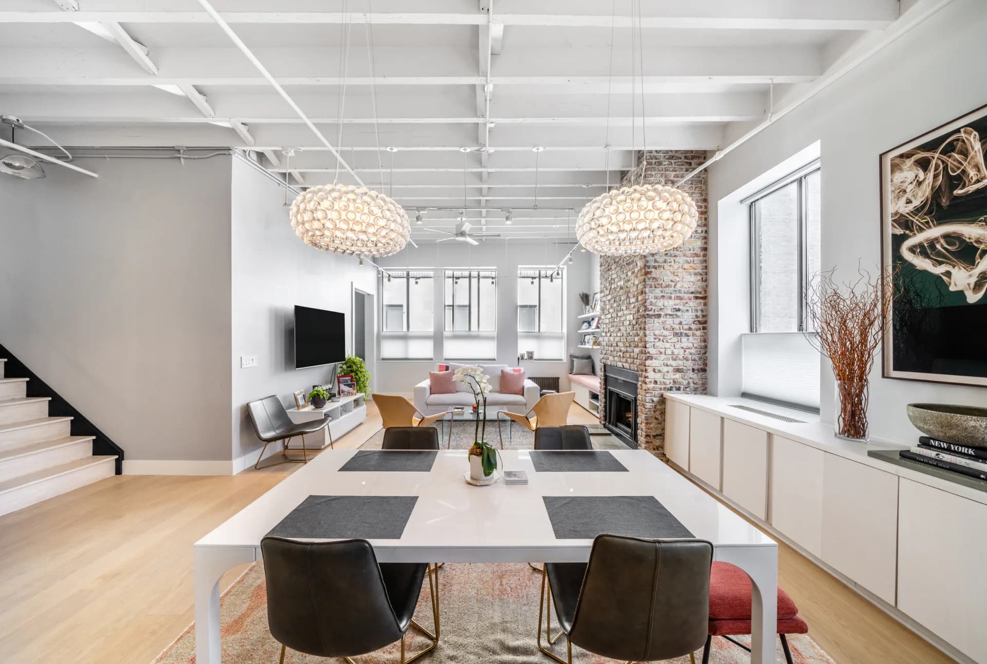 Modern loft interior with white exposed ceiling, concrete brick accent wall, pendant lighting, and open-plan living and dining areas by Matthew Ruopoli.