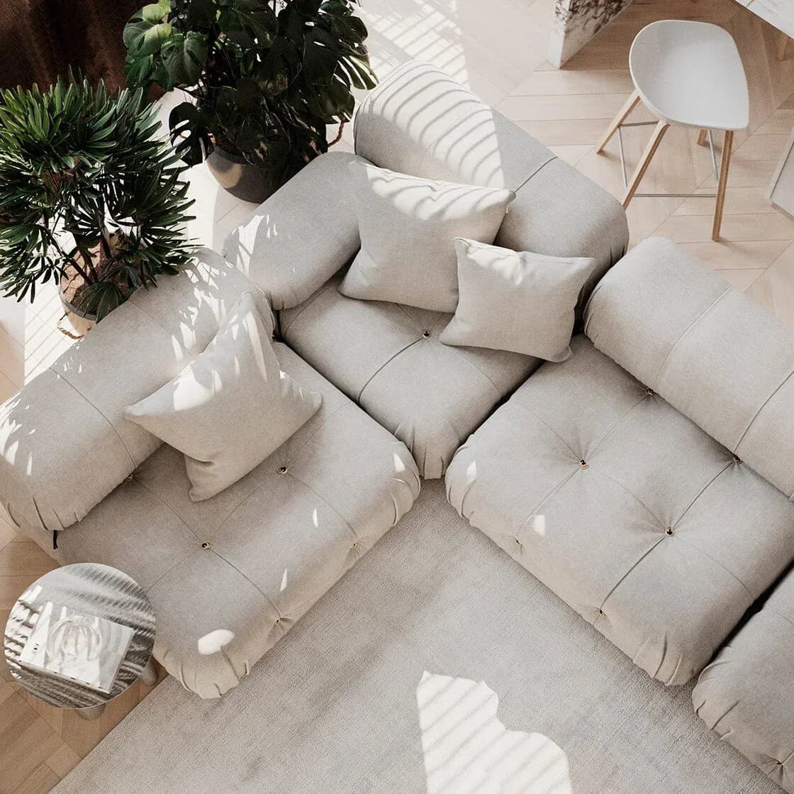 Minimalist living room with modular cream upholstered seating, natural light casting striped shadows, potted plants, and wooden accents by May WU.