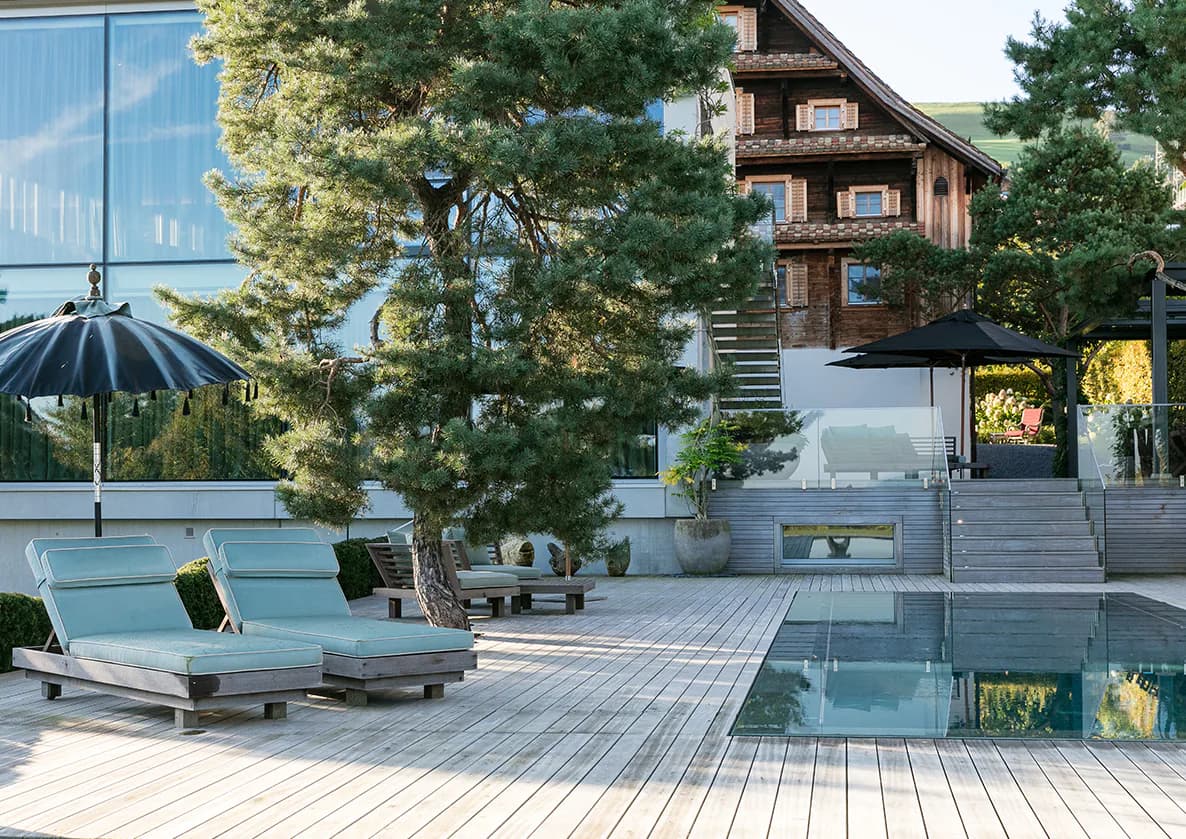Modern residential courtyard with pool, wooden deck, lounge chairs, and contemporary architecture by Maya Alawa.