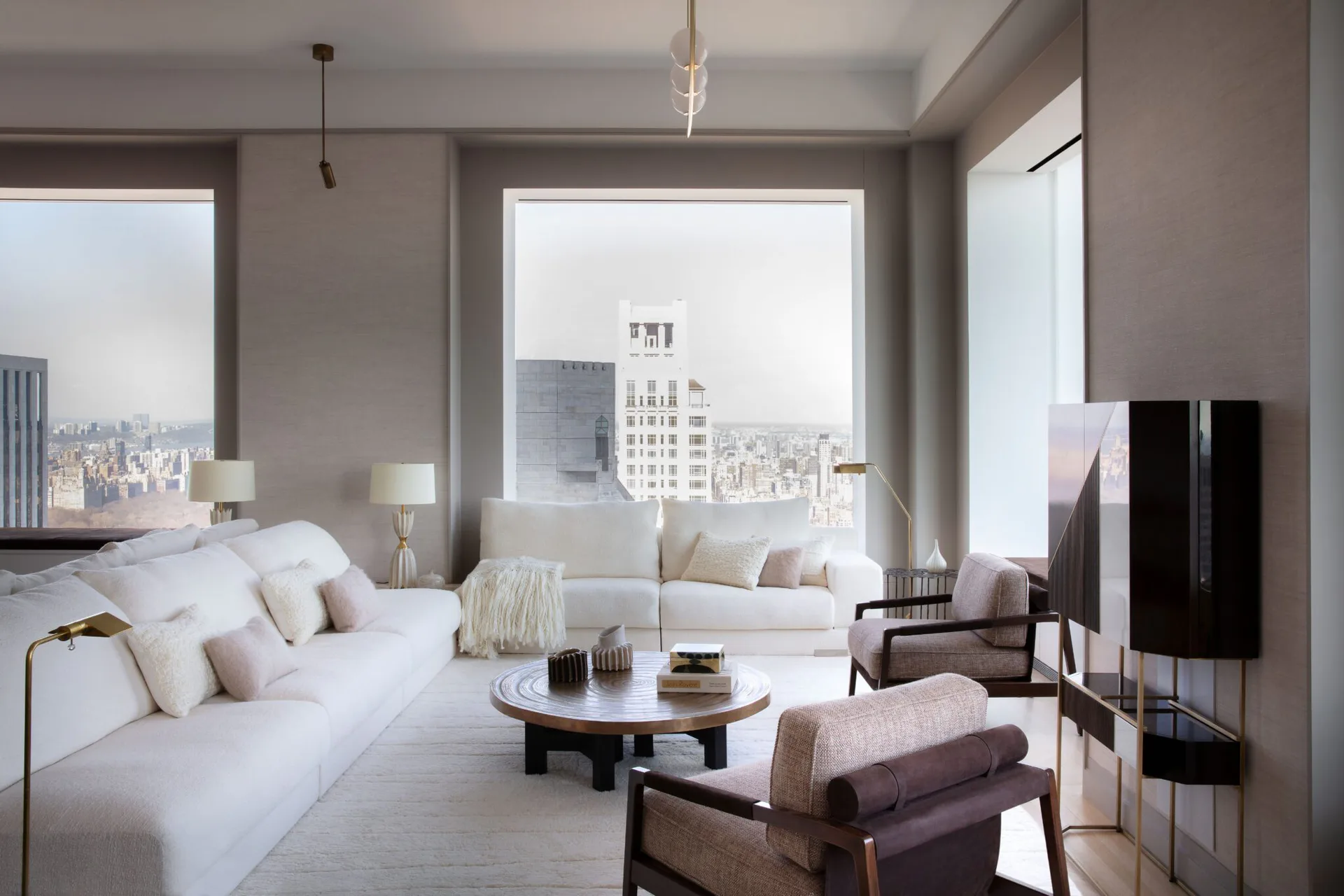 Minimalist high-rise bedroom suite with neutral palette, floor-to-ceiling windows overlooking cityscape, white bed with taupe accents, low wooden coffee table, and modern furnishings by Maylene Reyes.