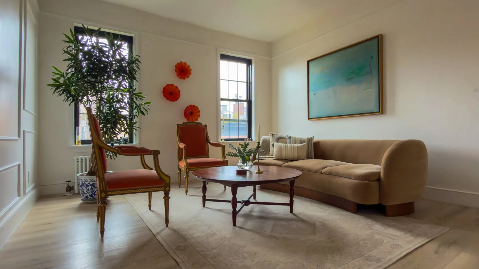 A contemporary living room with terracotta upholstered furniture, wooden accent chairs, abstract wall art, and decorative red spheres, rendered with synthetic lighting and perfect material composition by Mazen Eshak.