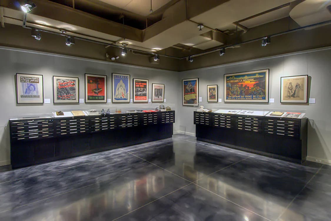 Gallery space with polished concrete floors, black flat-file storage cabinets, and framed artworks on white walls, designed by Melanie Freundlich.