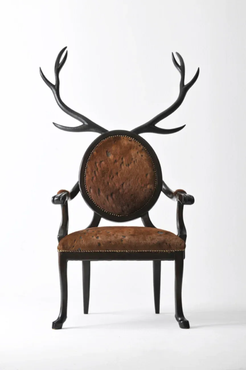 A sculptural chair with dark metal antler-like back and arms, brown leather upholstered seat and circular backrest by Merve Kahraman.
