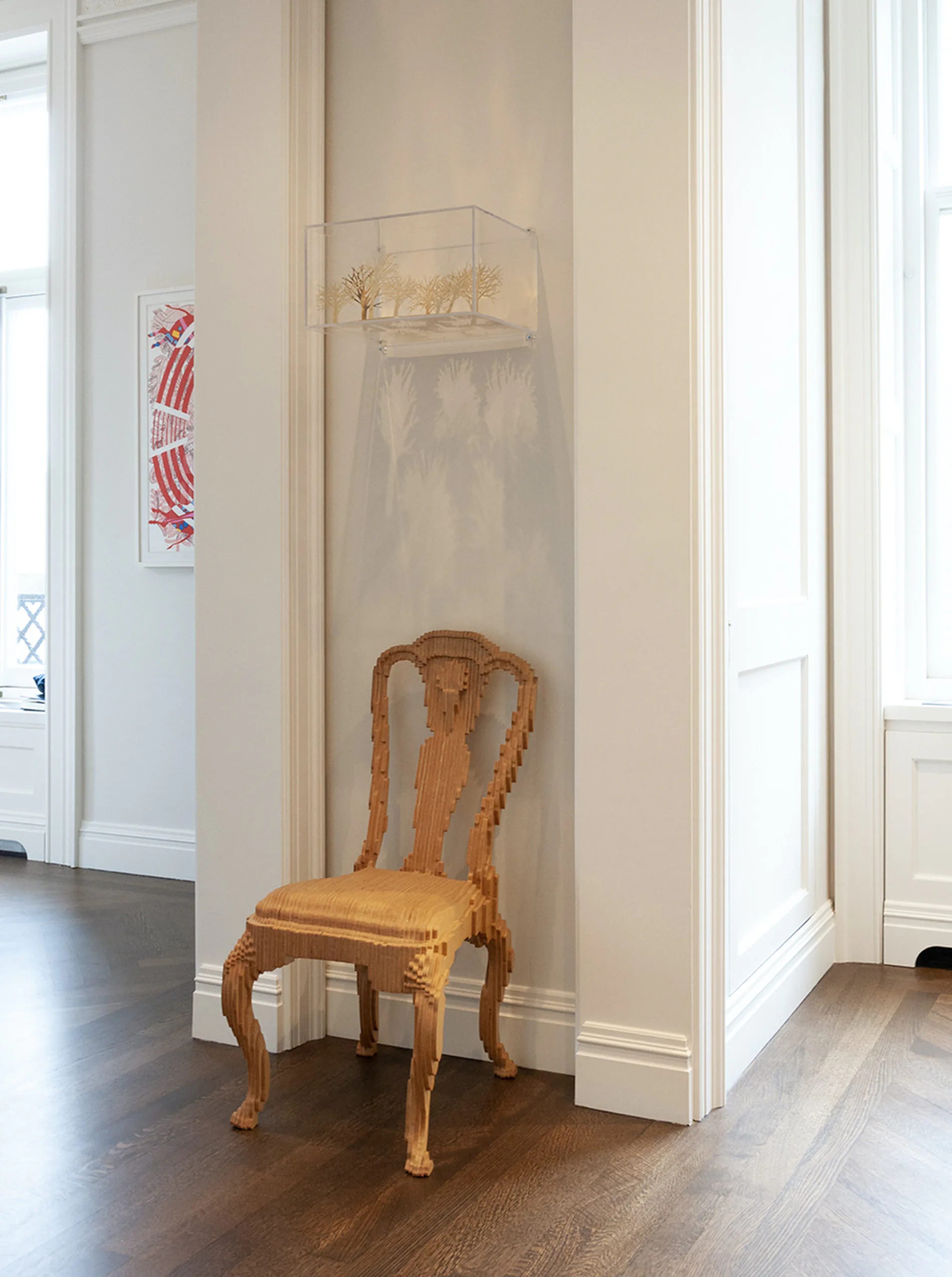 Minimalist entryway with beige walls, a wooden Queen Anne-style chair, floating shelf with decorative objects, and white trim by Meryl Scheinman.