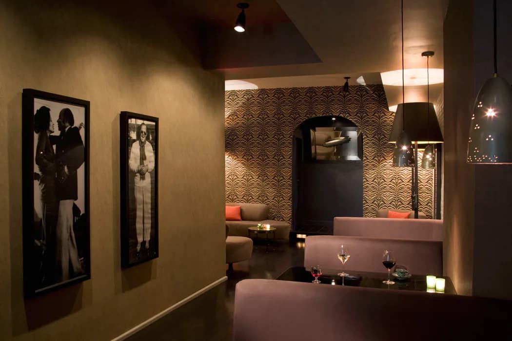 Modern retail interior with warm beige walls, black silhouette artwork, textured accent wall, display niche with ambient lighting, and sleek counters by Michael Pierce.