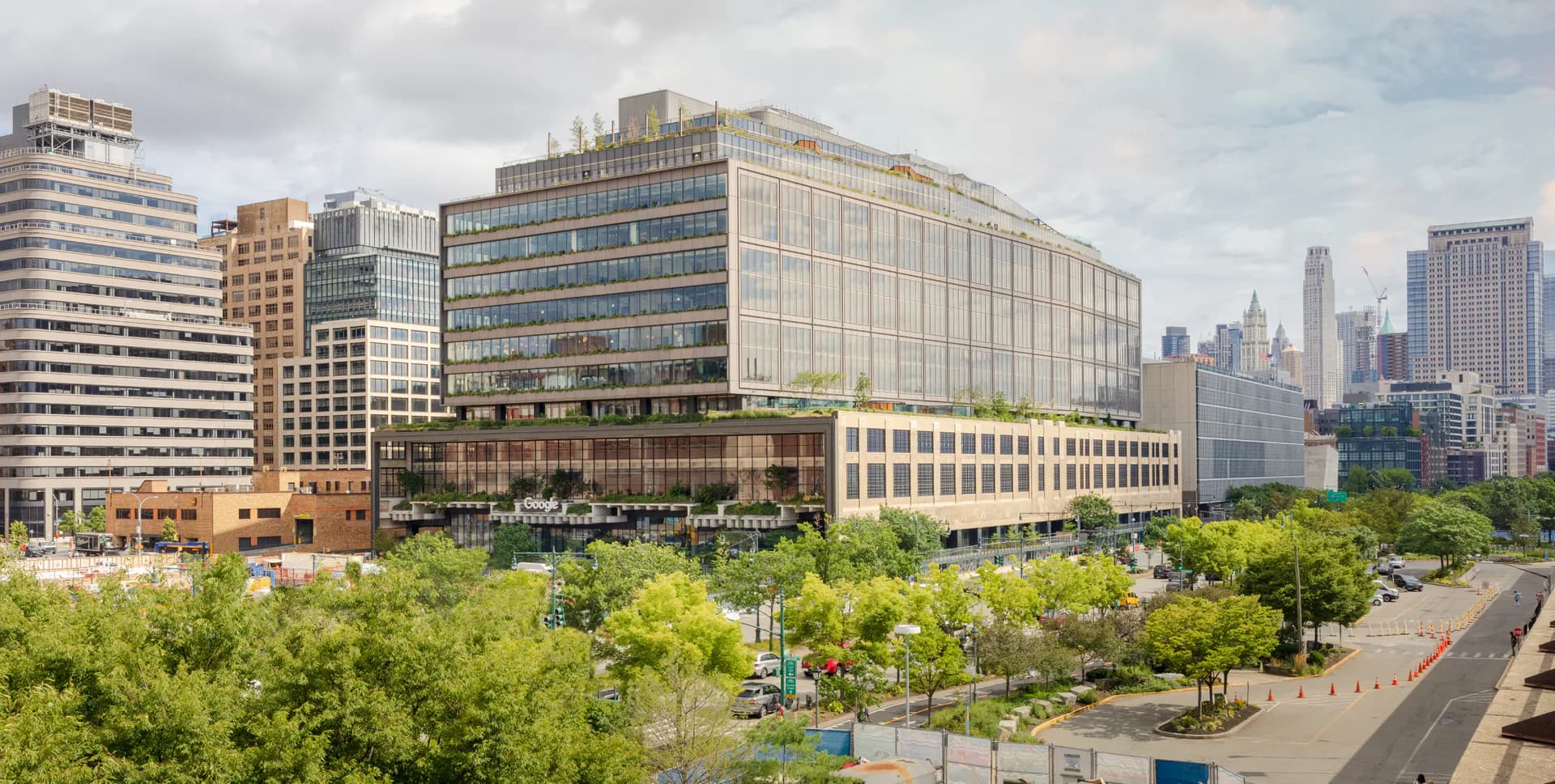 Contemporary mixed-use building with green plaza featuring trees and seating areas, urban skyline backdrop, designed by Michelle Romano.