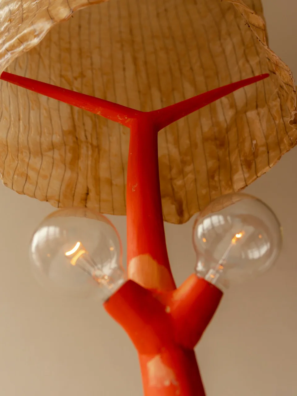 Red metal pendant light fixture with natural wood shade and exposed bulbs, contemporary design by Minjae Kim.