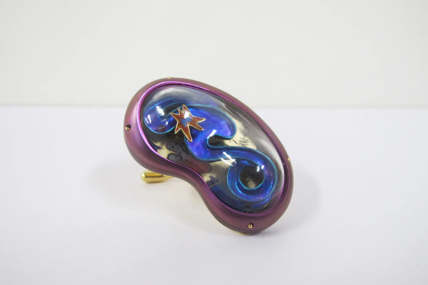 Purple and blue sculptural glass vessel with organic curved form and metallic accents, displayed against white background by Misha Kahn.