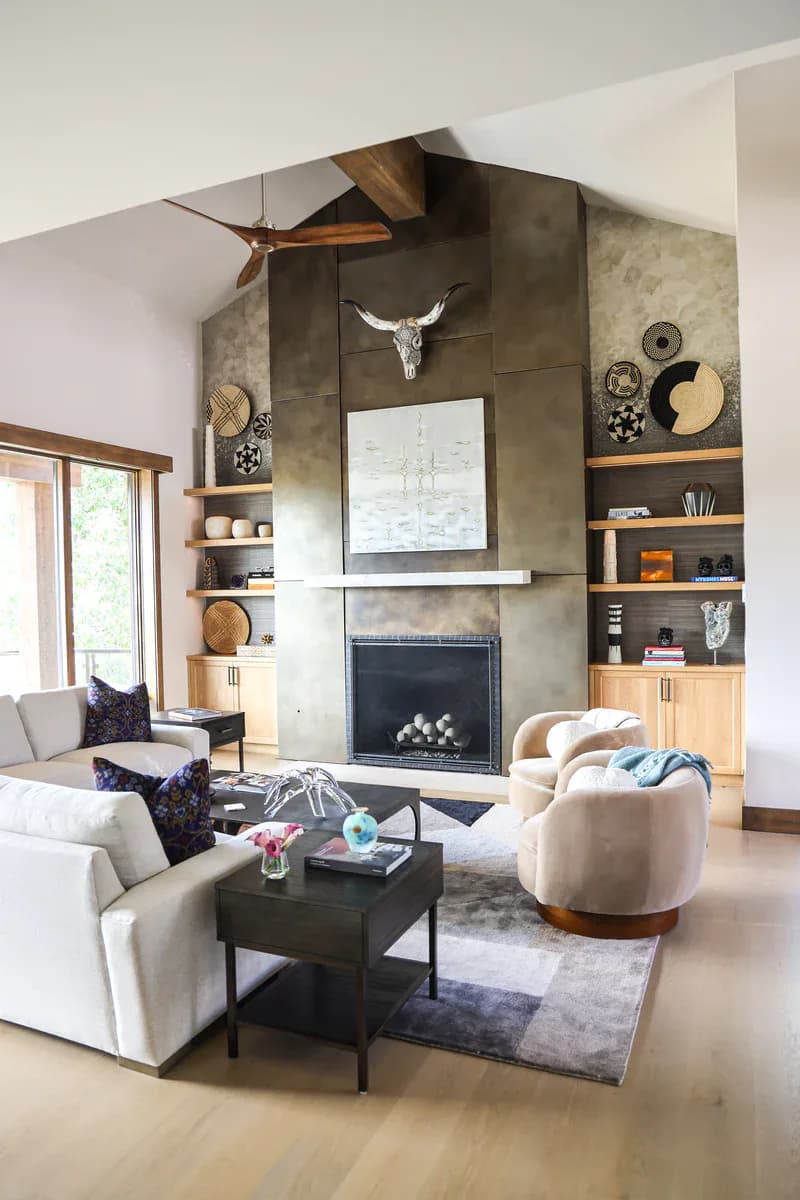 Modern living room with concrete fireplace wall, built-in shelving, cream seating, and decorative accessories by Mo Lebel.