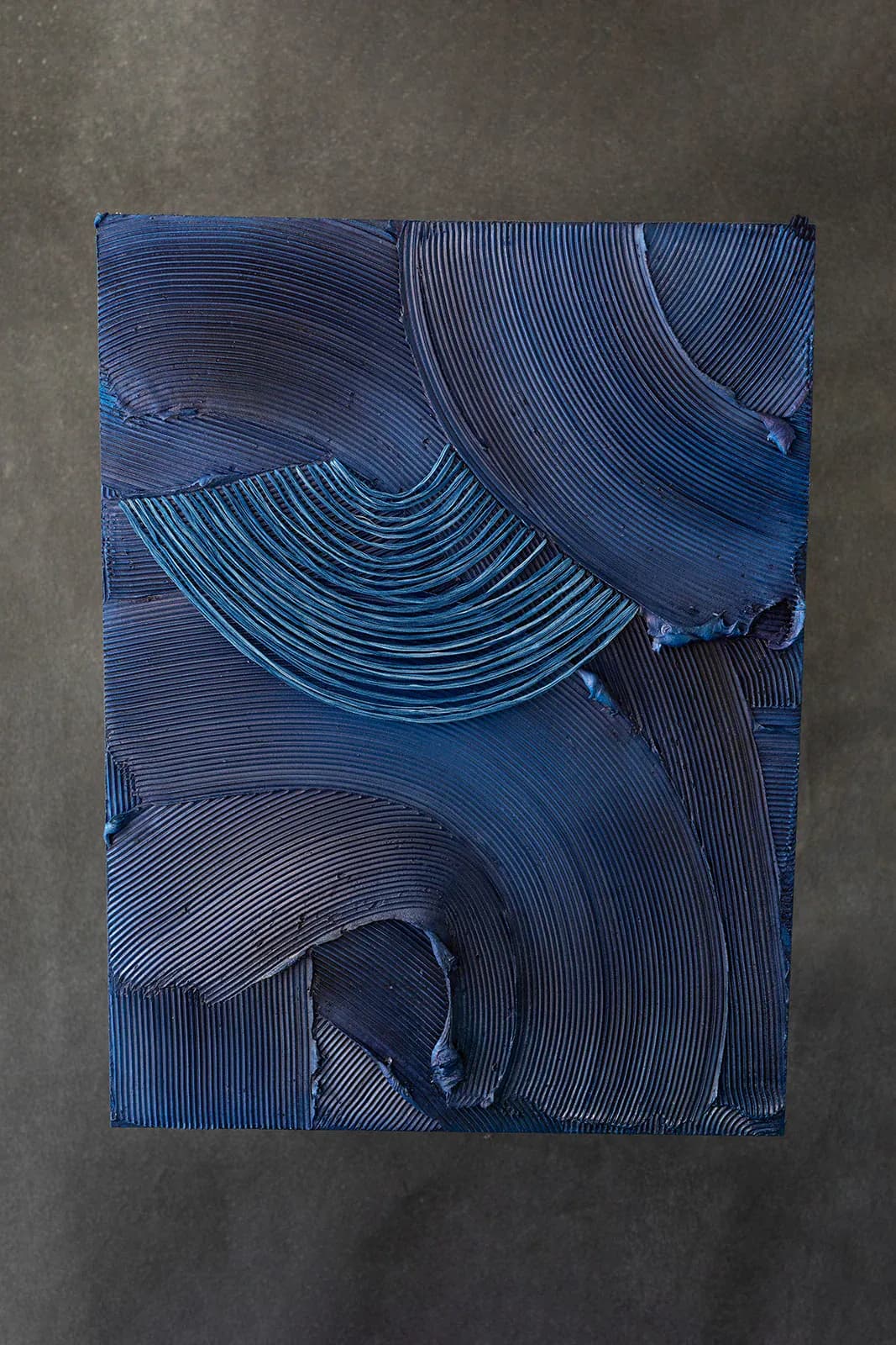 Abstract blue textured wall installation with layered curved linear patterns creating dimensional relief, by Monica Curiel.