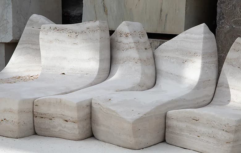 Curved concrete seating elements with organic forms arranged in a gallery space, showcasing sculptural furniture design by Najla El Zein.
