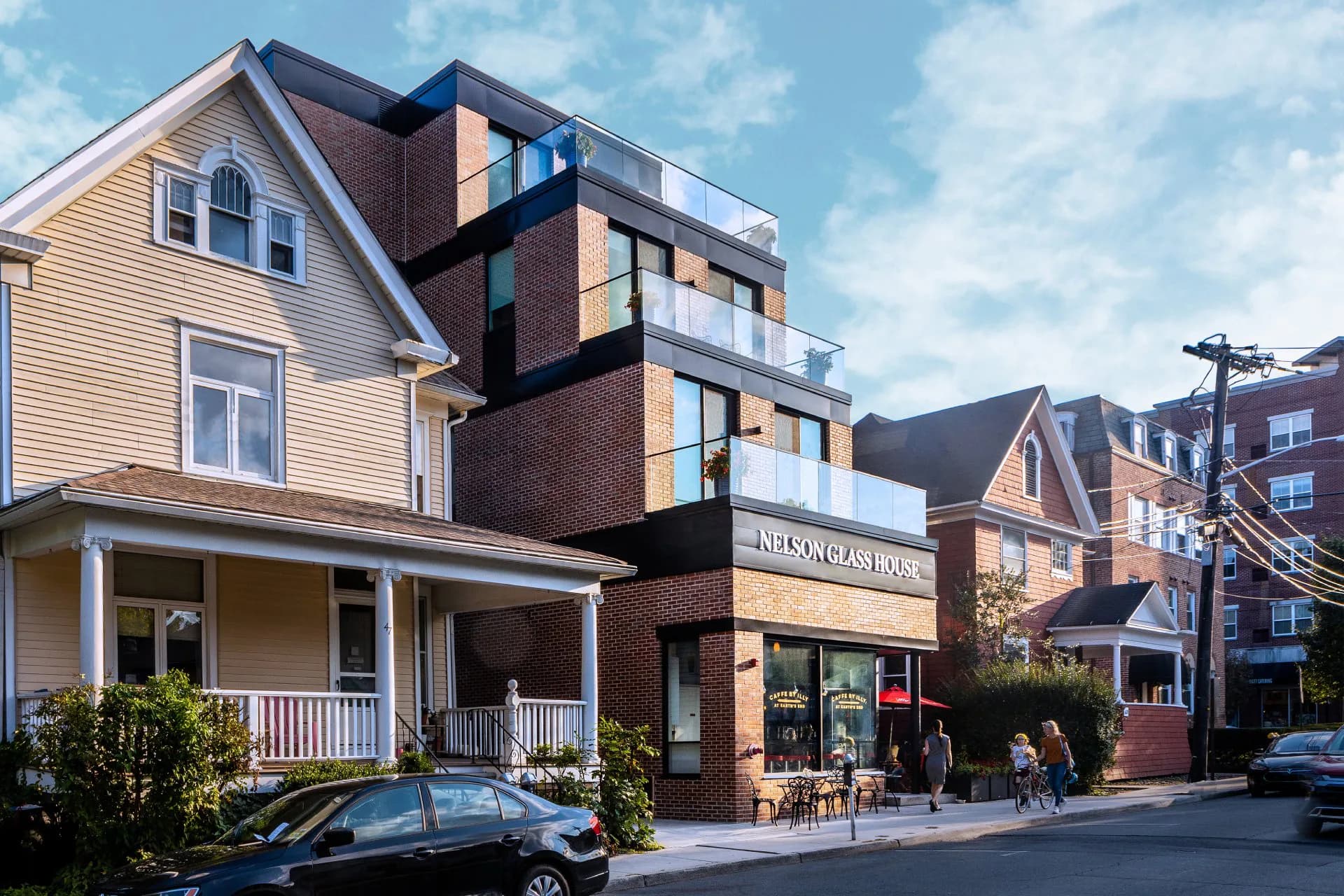 Mixed-use urban building with brick and light-colored facade featuring ground-floor retail and upper residential units, designed by Nancie Giardina.