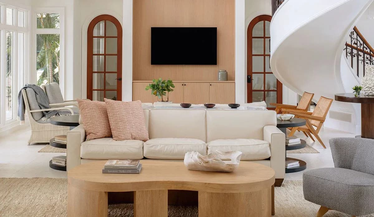Bright residential living room with cream sofa, natural wood coffee table, arched doorways, and warm beige tones throughout, designed by Naomi Stroh.