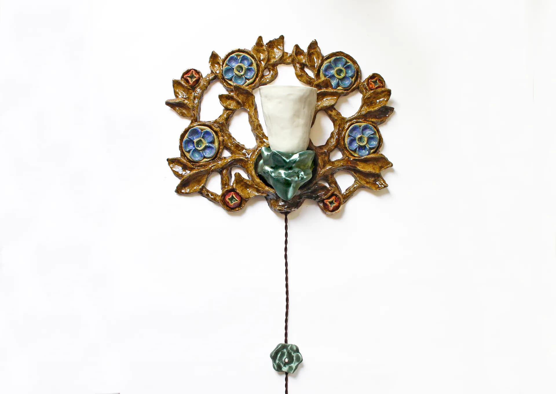 Ornate brass brooch with cream-colored central pendant, blue enamel circular details, and dangling green stone accent by Natalia Triantafylli.