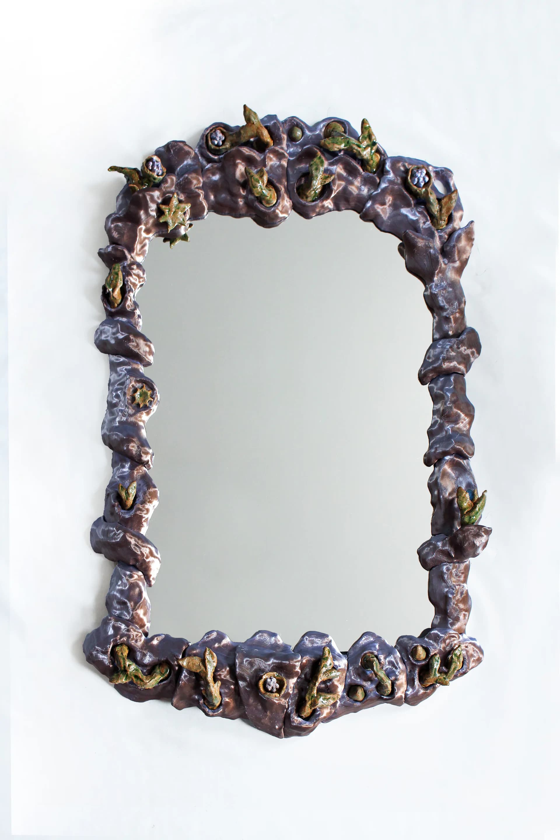 Ornate decorative mirror frame with sculptural purple and gold embellishments, featuring organic forms and detailed metalwork by Natalia Triantafylli.