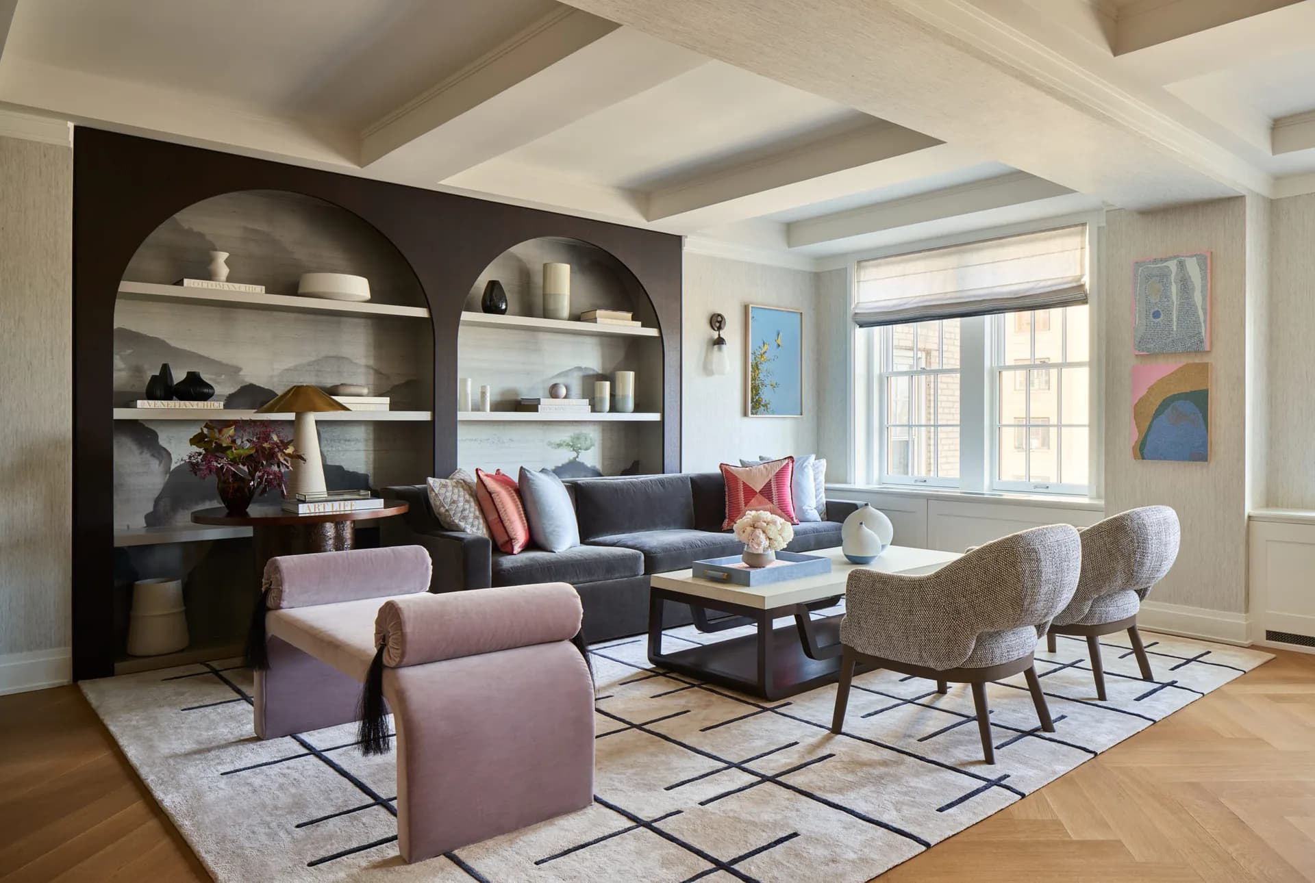 Contemporary living room with dark archway shelving, purple accent chairs, navy sofa, geometric patterned rug, and coffered ceiling by Natalia Tutka.