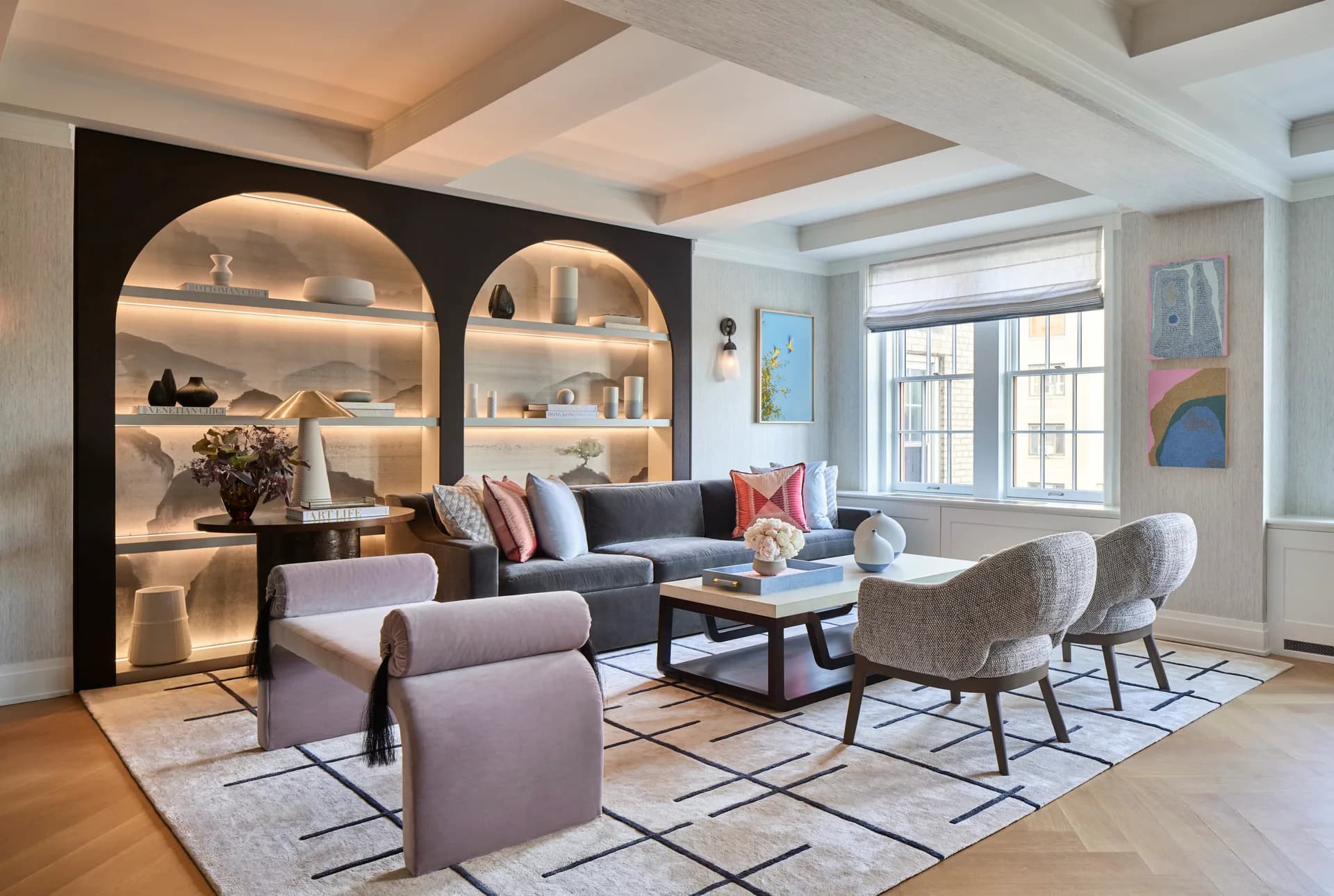Contemporary living room with arched black shelving, gray seating, geometric area rug, and natural wood flooring by Natalia Tutka.