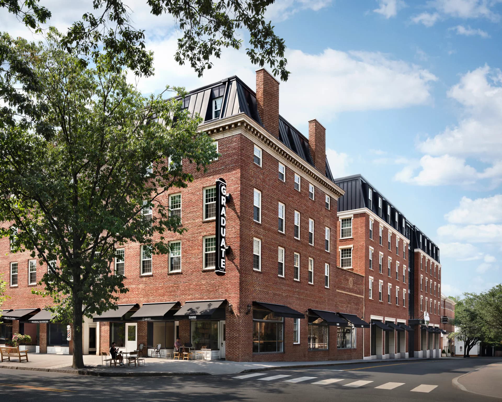 Brick Georgian-style building with mansard roof and ground-floor retail space, featuring large windows and classical proportions by Nduka Aliberi.