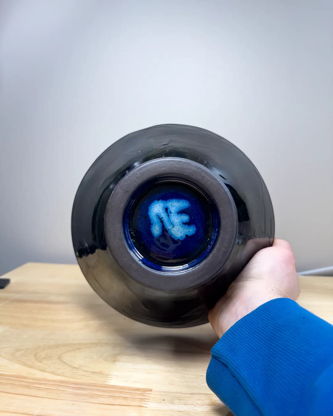 Black spherical product with glowing blue interior held in hand against wooden surface, designed by Nicholas Talamo (WorksbyNET).