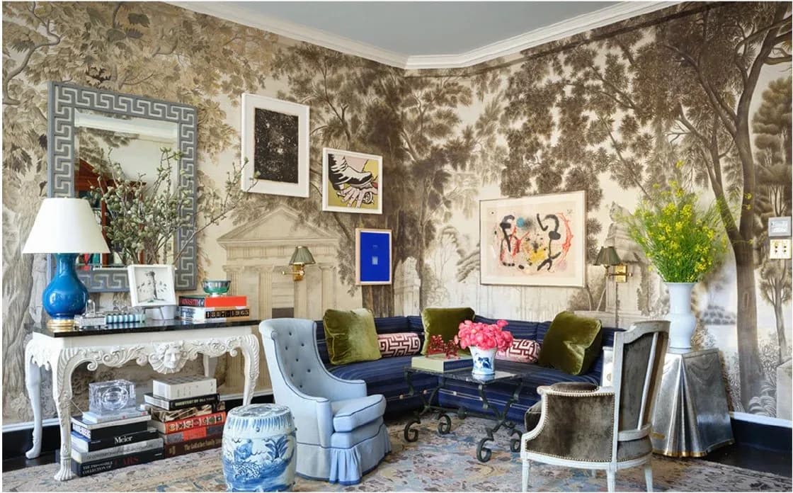 Eclectic living room with chinoiserie wallpaper, blue upholstered seating, gallery wall, console table with lamp, and decorative accessories by Nick Olsen.