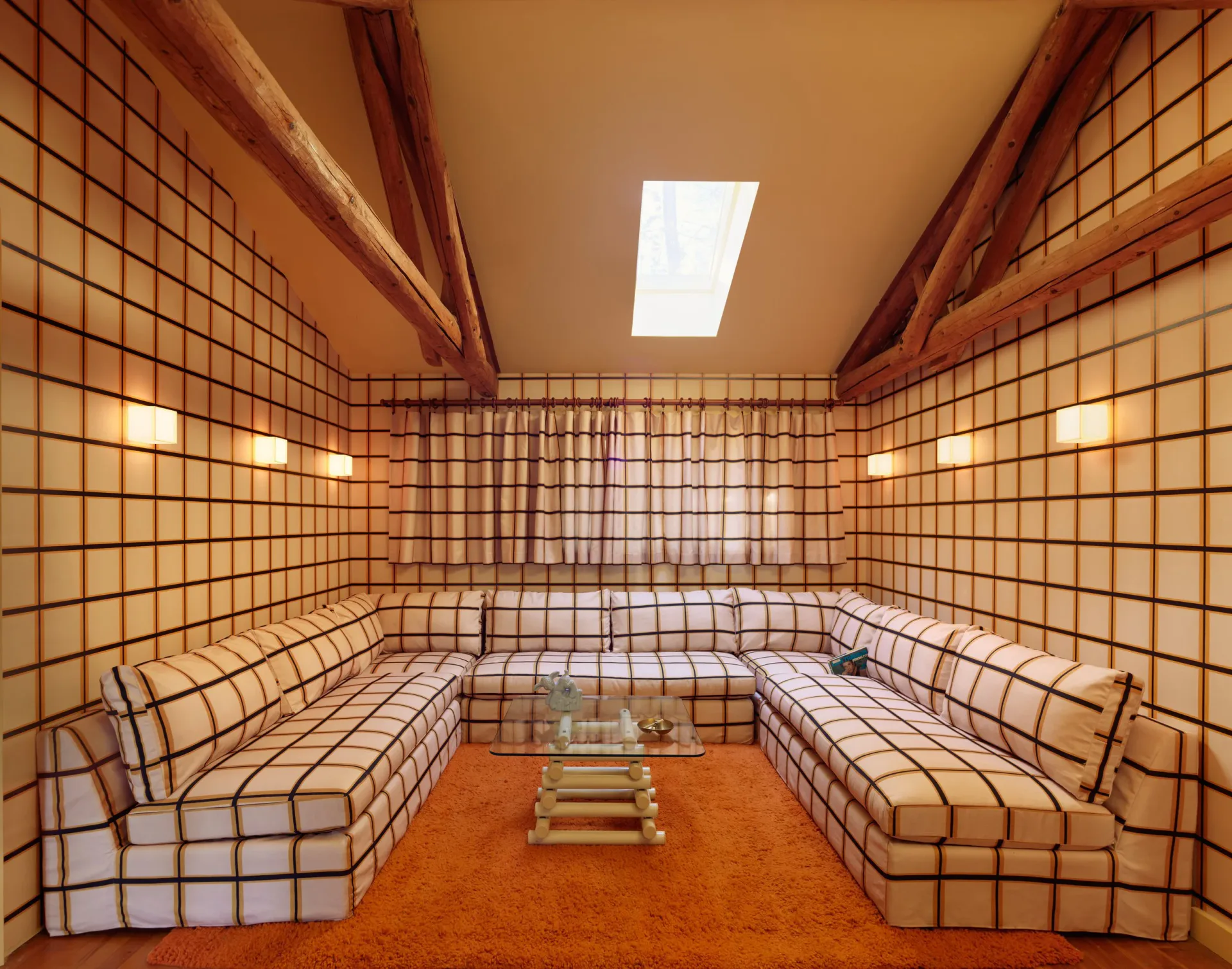 Symmetrical interior with cream-tiled walls, wooden beams, built-in seating, and skylight by Nick Spain.