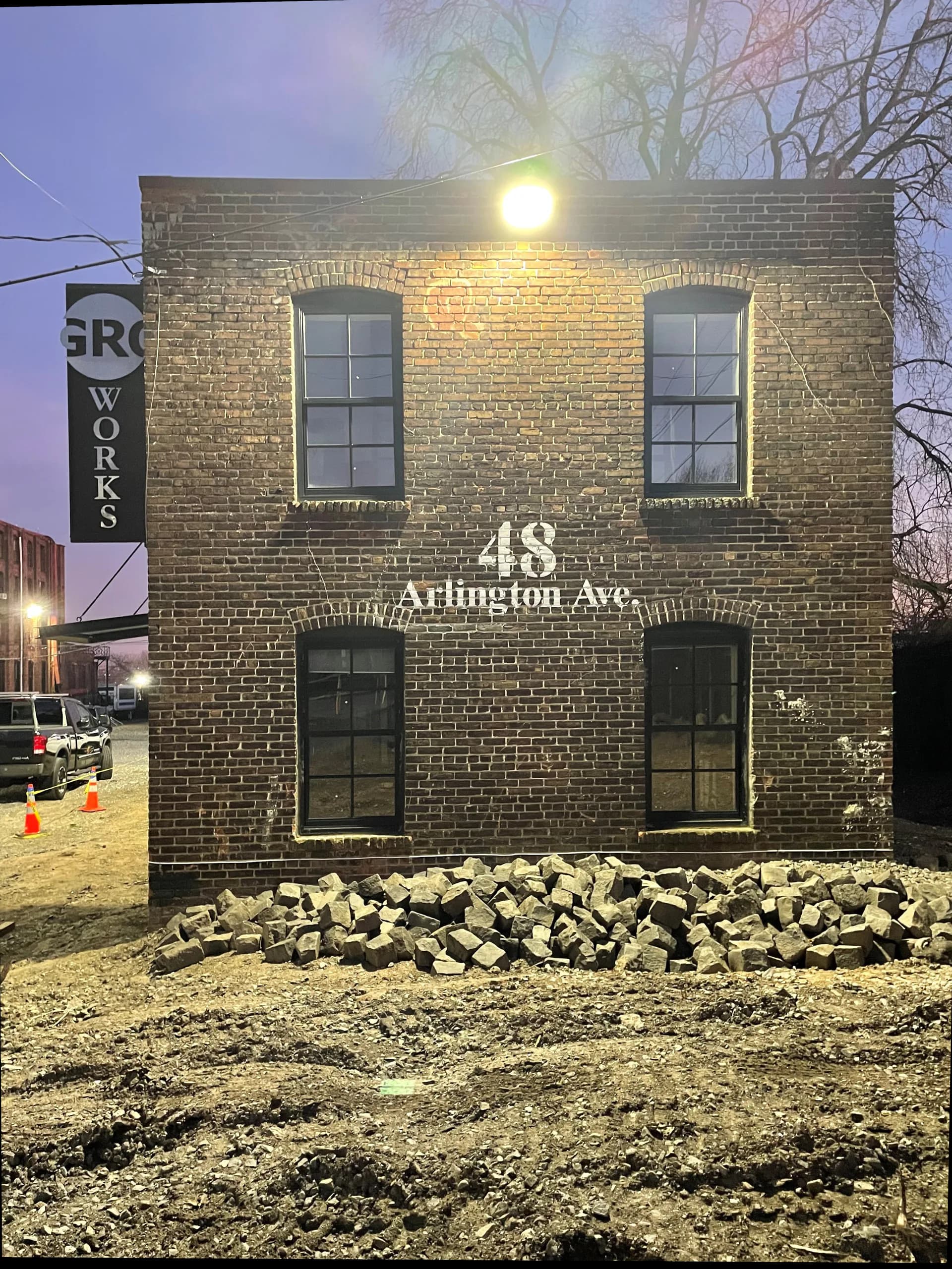 Brick facade of 48 Arlington Ave illuminated at dusk, featuring symmetrical arched windows and ground-level stonework, designed by Nicole Robertson.