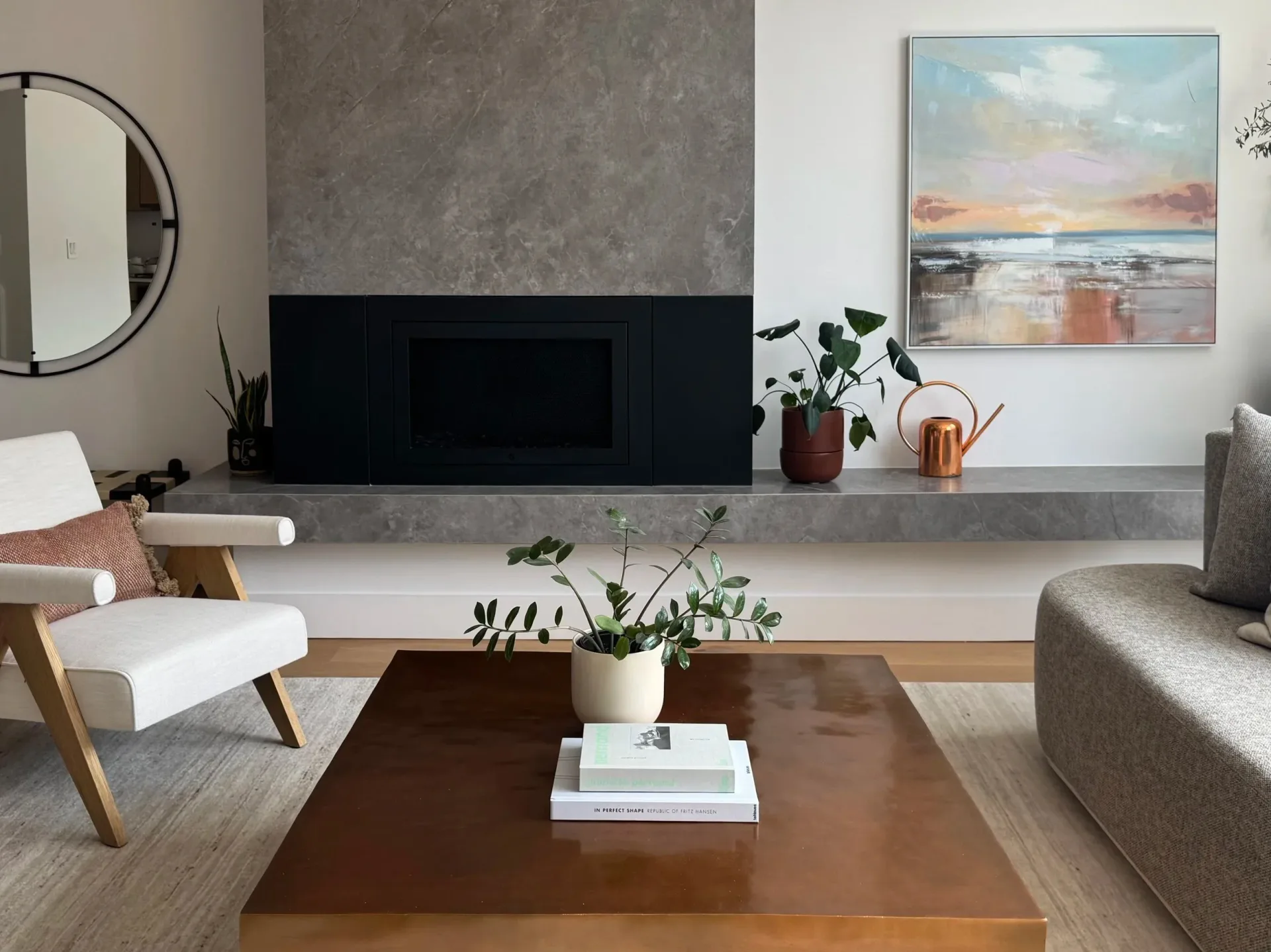 Modern living room with concrete fireplace surround, wood coffee table, neutral upholstered seating, and coastal artwork by Nina Fisher.