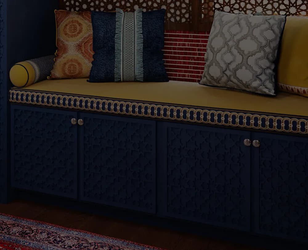 Navy upholstered bench with brass trim and patterned pillows in jewel tones displayed in an interior design portfolio piece by Nivi Ravi.