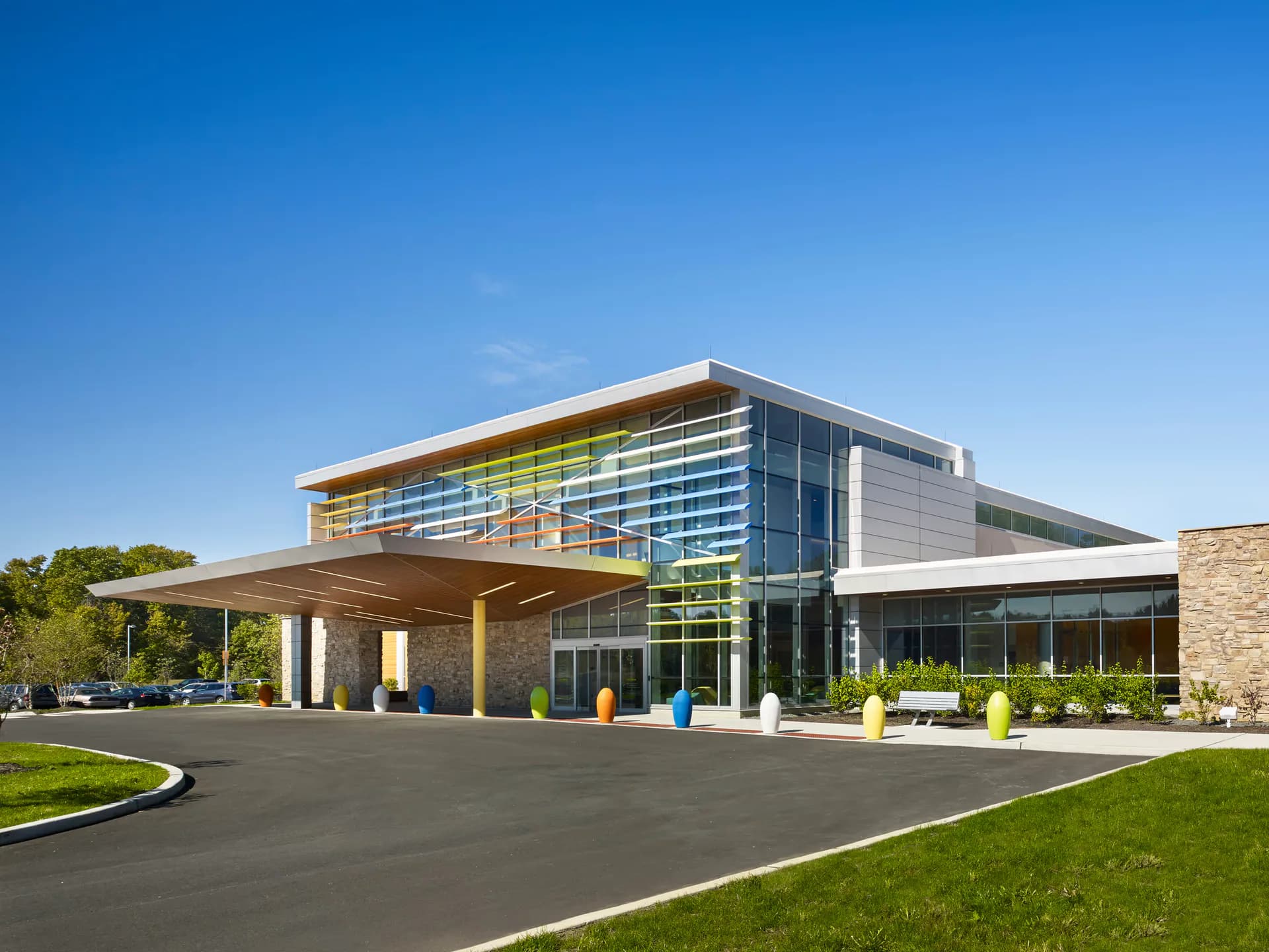 Modern institutional building with glazed upper facade, warm wood accents, and manicured grounds designed by Noah Tolson.