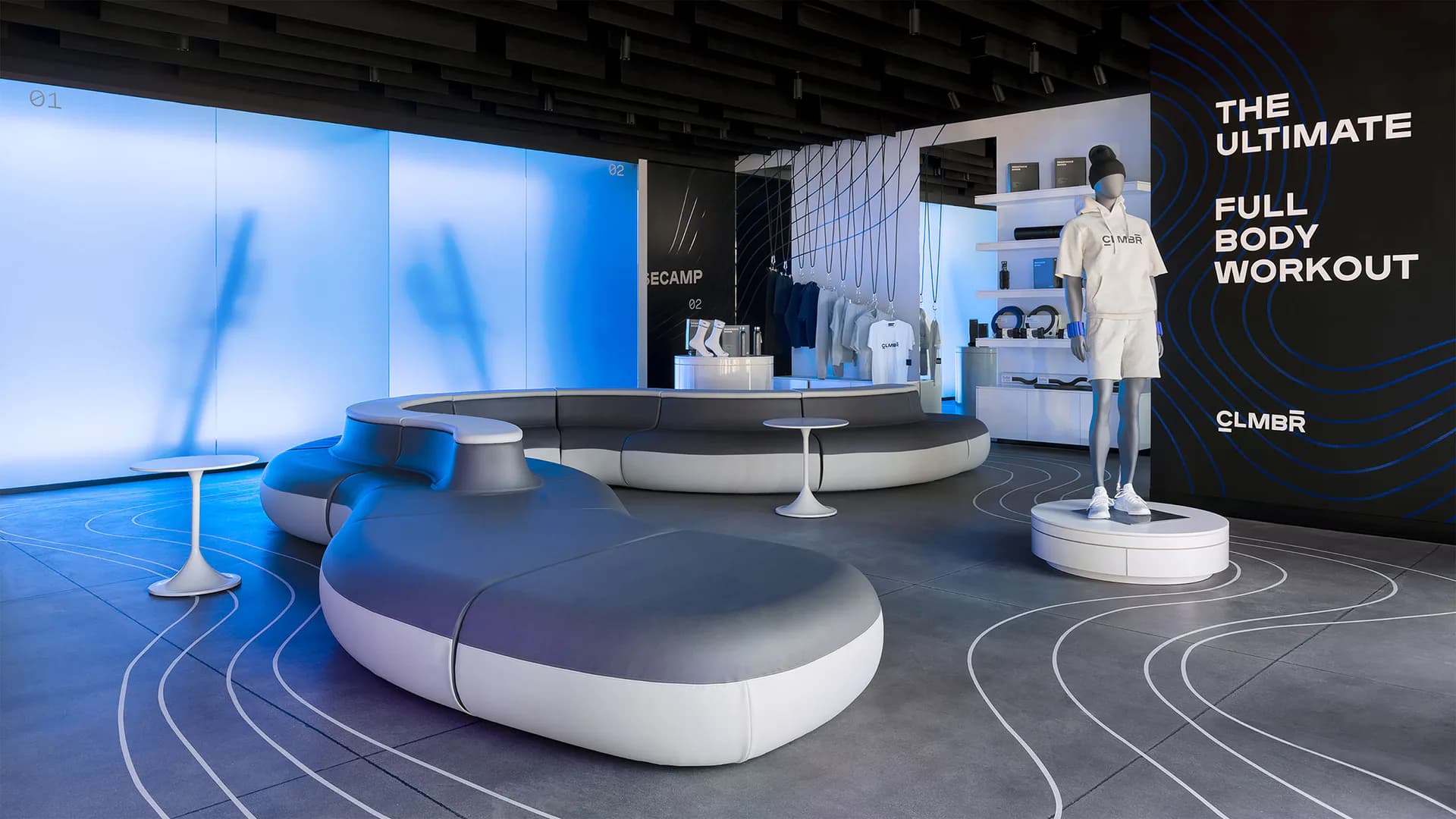 Modern fitness studio with blue-lit walls, curved furniture pieces, and geometric floor patterns, branded as 'The Ultimate Full Body Workout' by Noah Waxman.