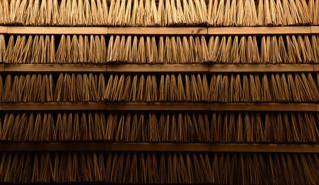 Layered wooden shingle roof detail showing rows of overlapping tan and brown cedar shakes in graduating tones, architectural photography by Osamu Tsuchiya.